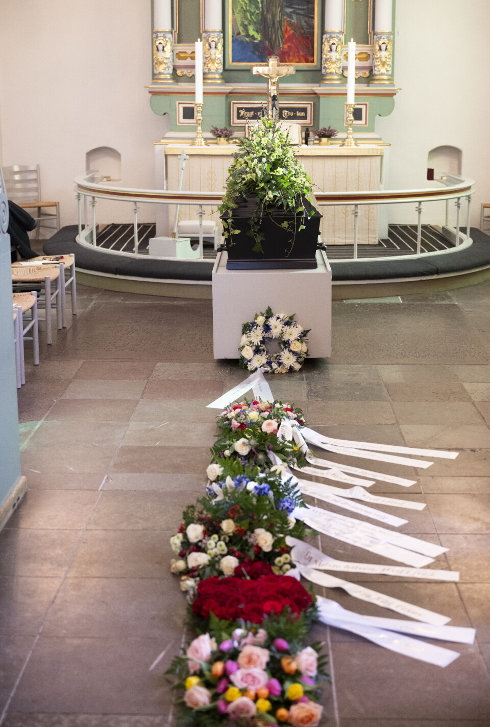 Den sortlakerede kiste var flot pyntet, ligesom hele gulvet var fyldt med kranse og blomster.