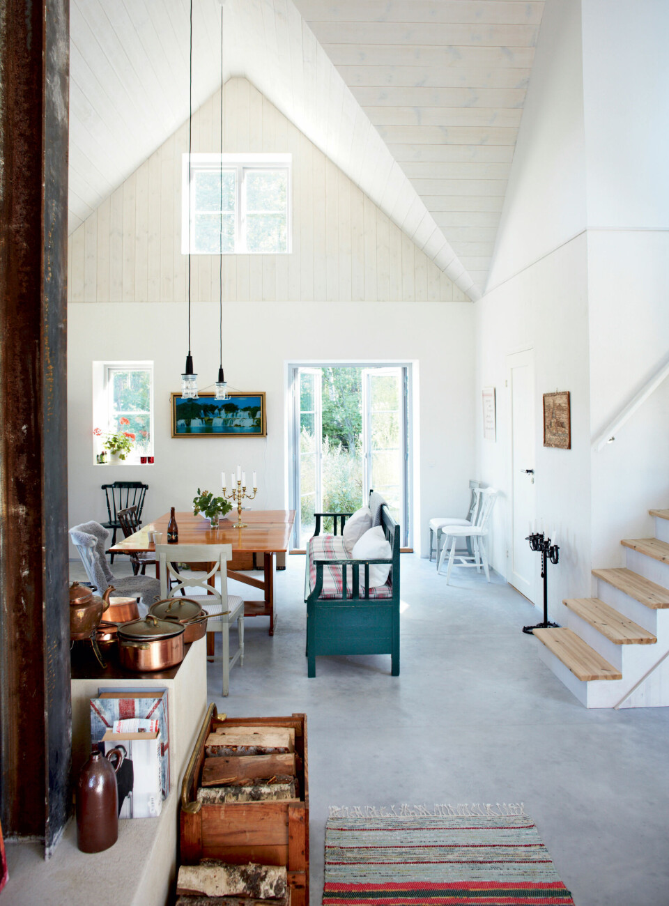 Køkkenalrummet domineres af den blå slagbænk, som Tomas har arvet af sin farmor og farfar. Bord og stole er gamle. På væggen hænger et kitschet vandfaldsmaleri med indbygget lys og fuglekvidder, og over bordet hænger simple murerlamper fra et byggemarked.