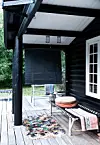 Sommerhusets terrasse binder de to træhuse sammen og er indrettet med flere små hyggekroge.