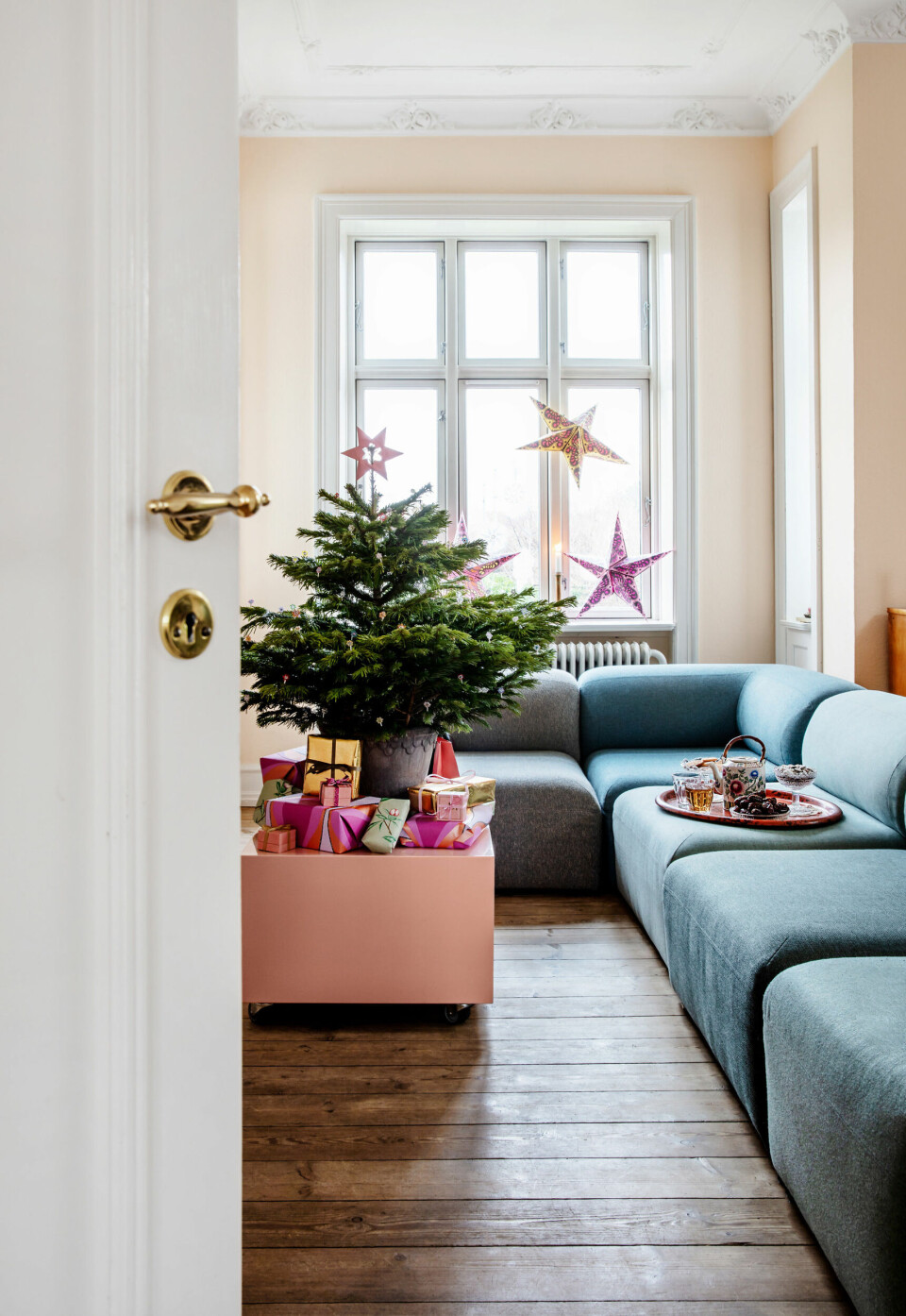 I stuen har Shiri malet med en orange farve, som hun hældte en masse hvid maling i, for at få en lys pastelfarve. Som sofabord bruger Shiri en rosa kasse med opbevaring, som hun engang lavede til en butik.