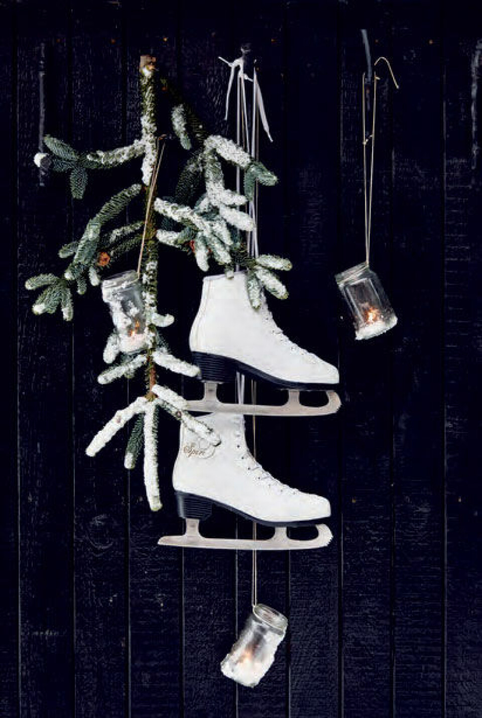 Et par skøjter, en grangren og et par syltetøjsglas med lys i skaber hyggelig vinterstemning med et snuptag.