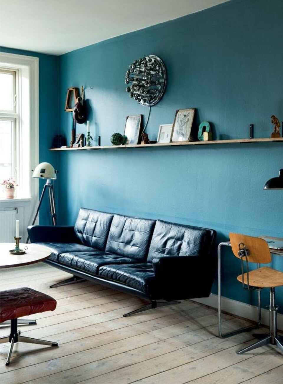 I stuen står en patineret lædersofa som en flot kontrast til den blå væg. Den smukke væglampe er en Sciolari lampe, mens gulvlampen er en gammel Hanau lampe, som Michael har fundet på et loppemarked i Tyskland. Til højre anes det bedste fund, en gammel Egon Eiermann-stol.