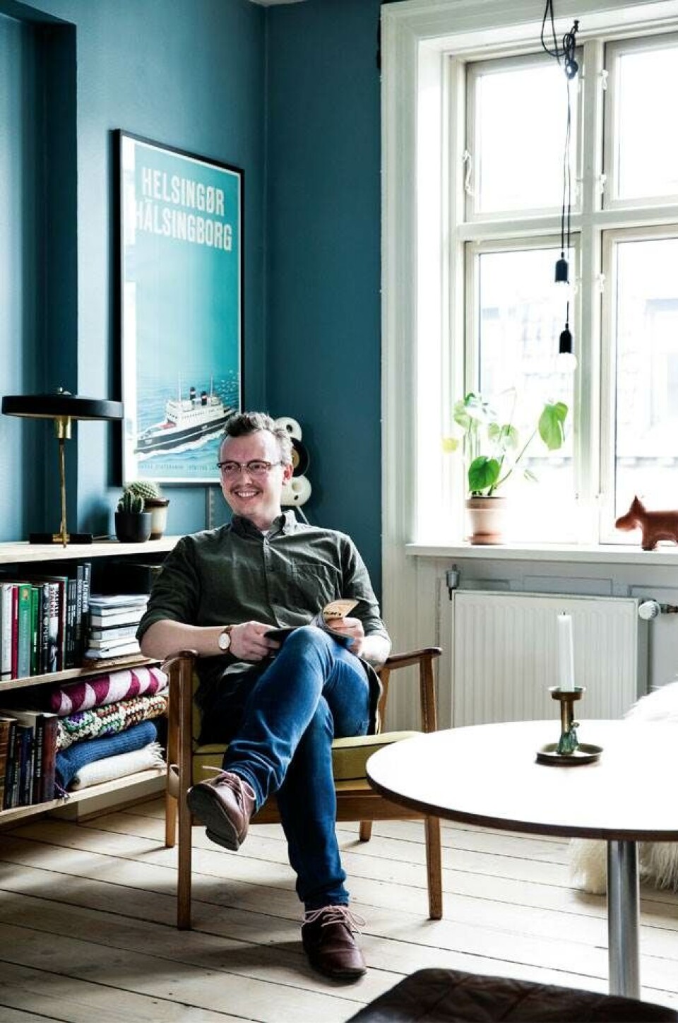 Michael går ikke op i, hvem der har tegnet møblerne, bare de er specielle og i god kvalitet som lænestolen, der bare var helt rigtig i farven og rar at sidde i. Vintage færgeplakaten er fra Helsingør ligesom Thomas. Den flotte bordlampe er en gammel Louis Kalff-lampe.