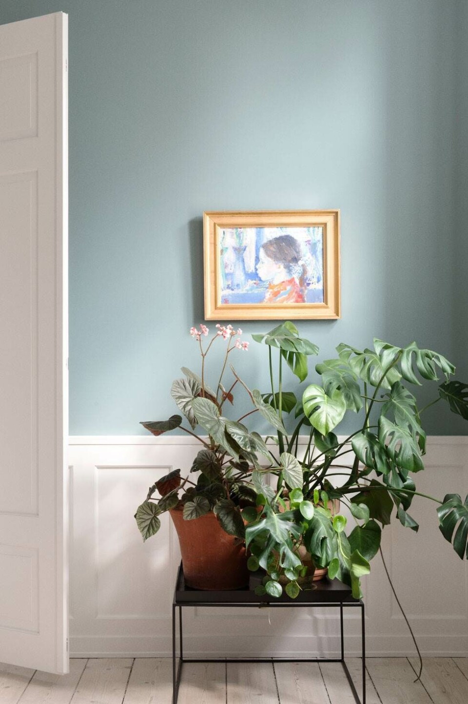 På sofabordet fra Hay har Trine samlet sine grønne planter. Billedet på væggen er af Poul S. Nielsen, der blev kaldt den blå maler, og som har boet i lejligheden, hvor han også har malet dette portræt af naboens datter. Trine fandt værket på Lauritz.com. Kunstneren var meget glad for blå, og alt i lejligheden var malet blåt, da Trine overtog lejligheden, så derfor var det svært at komme udenom farven blå i istandsættelsen. Foto: Gyrithe Lemche