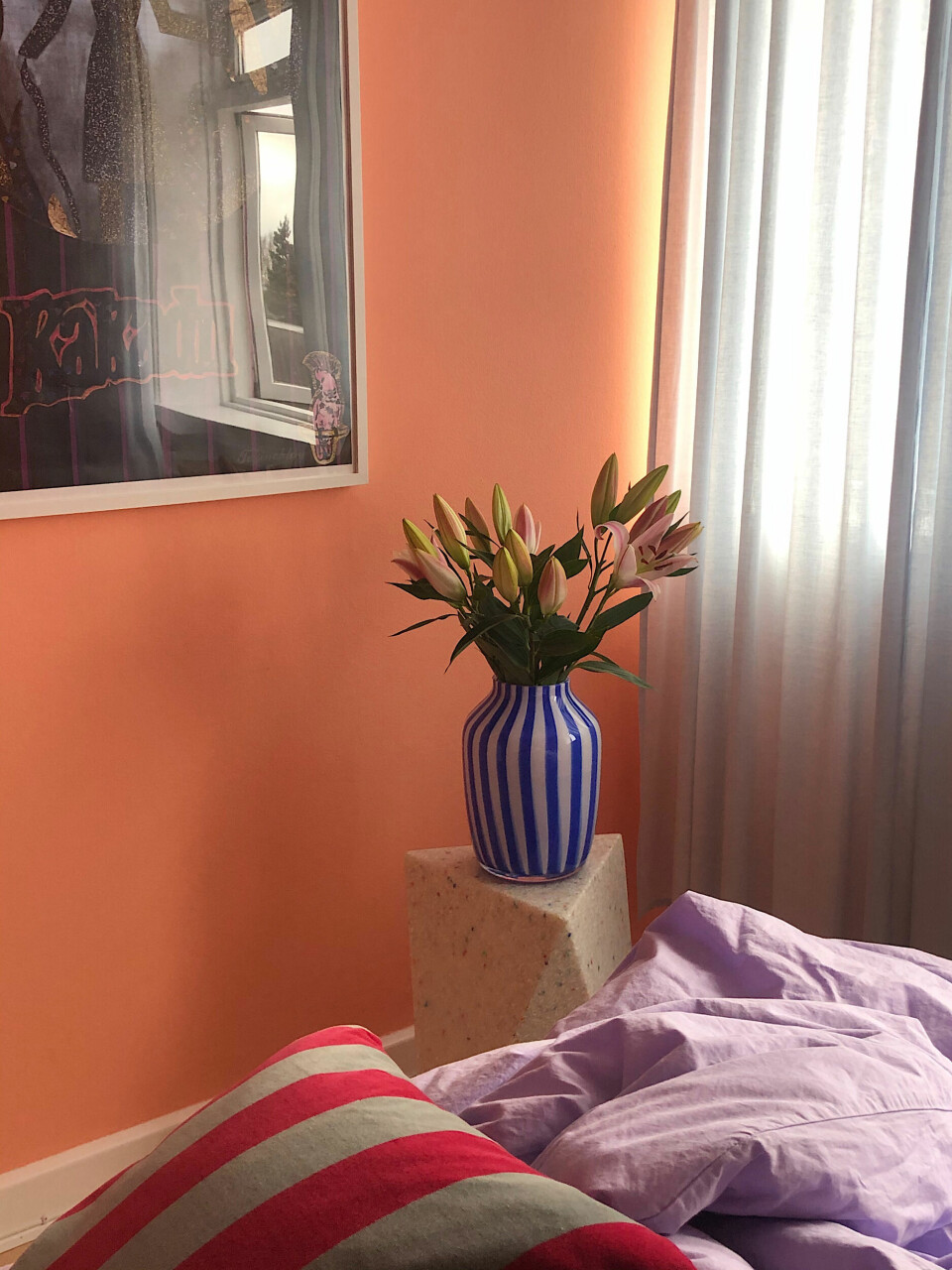 Lyserøde liljer i vasen fra HAY, plakat fra Stilleben, gardiner fra IKEA og sengetøj fra Magasin.