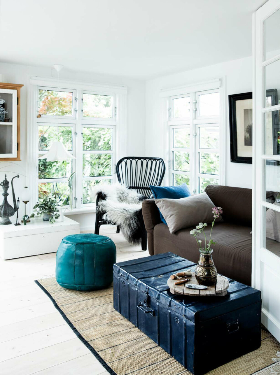 I kurvestolen fra Ikea ligger et lammeskind købt på Tivolis hyggelige julemarked. Sofaen fulgte med huset, puffen er en gave, kufferten er et arvestykke og tæppet er lavet af Leenas genbo.