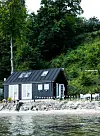 Huset ligger i forreste række ned til vandet. Tagryggen består blandt andet af en stor limtræsbjælke, der er belagt med kobber i hver ende.