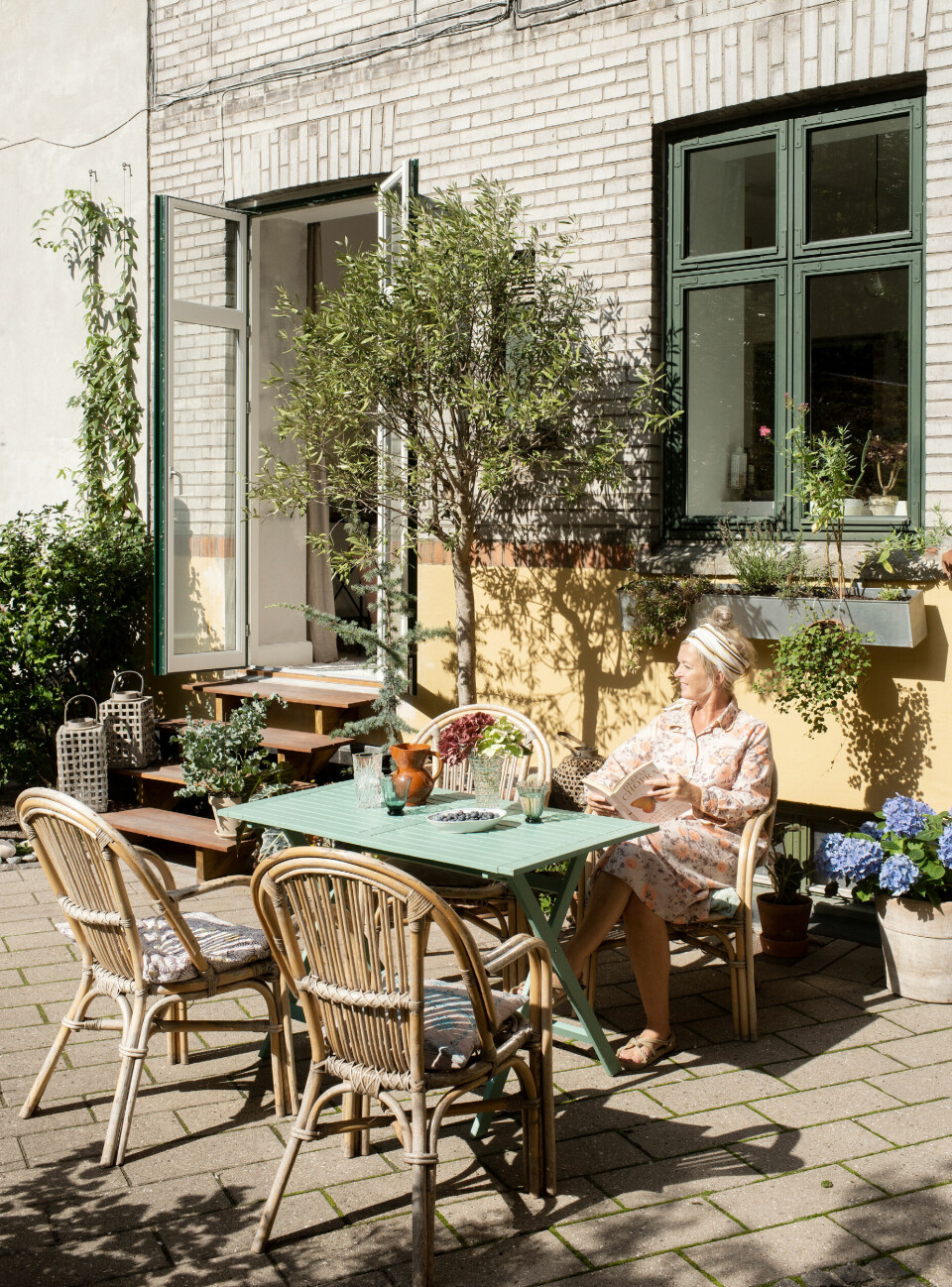 Karina er medlem af gårdlauget og hjælper med at gøre gården grøn og hyggelig med masser af krukker, havemøbler og hængekøjer. Havemøblerne har hun fundet på et loppemarked og selv malet, mens bambusstolene er fundet på DBA.