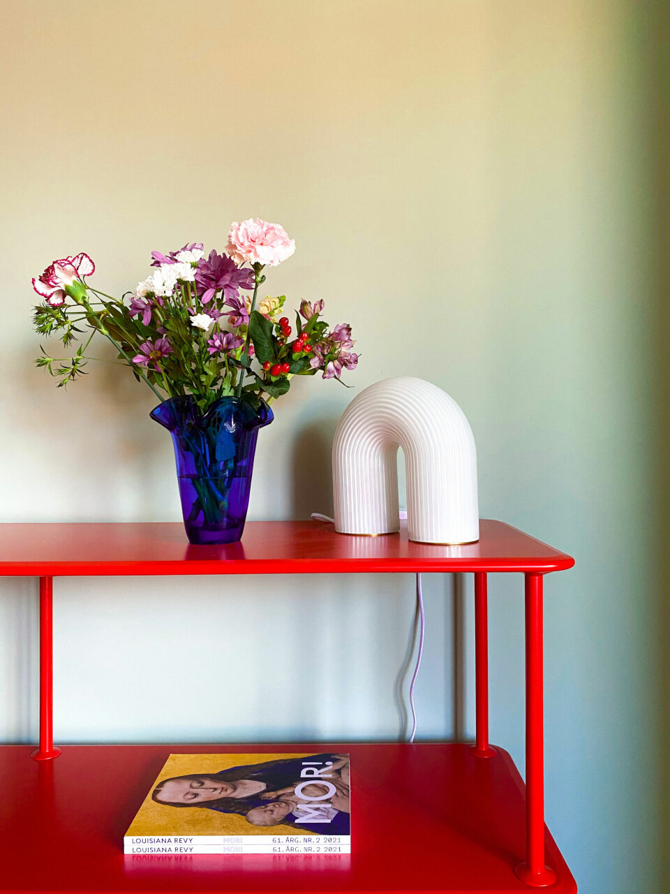 Den blå vase har Susanne købt hos Heidis genbrugsguld. Den røde reol er fra Montana.