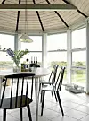 Fra spisebordet erder udsigt over hele området gennem de store panoramavinduer. Glasvasen er købt i Bilka, tedåserne er fra Kushmi Tea, og glasflasken med korkprop fra Muuto. I baggrunden står en Kubusstage, der fås hos Paustian.