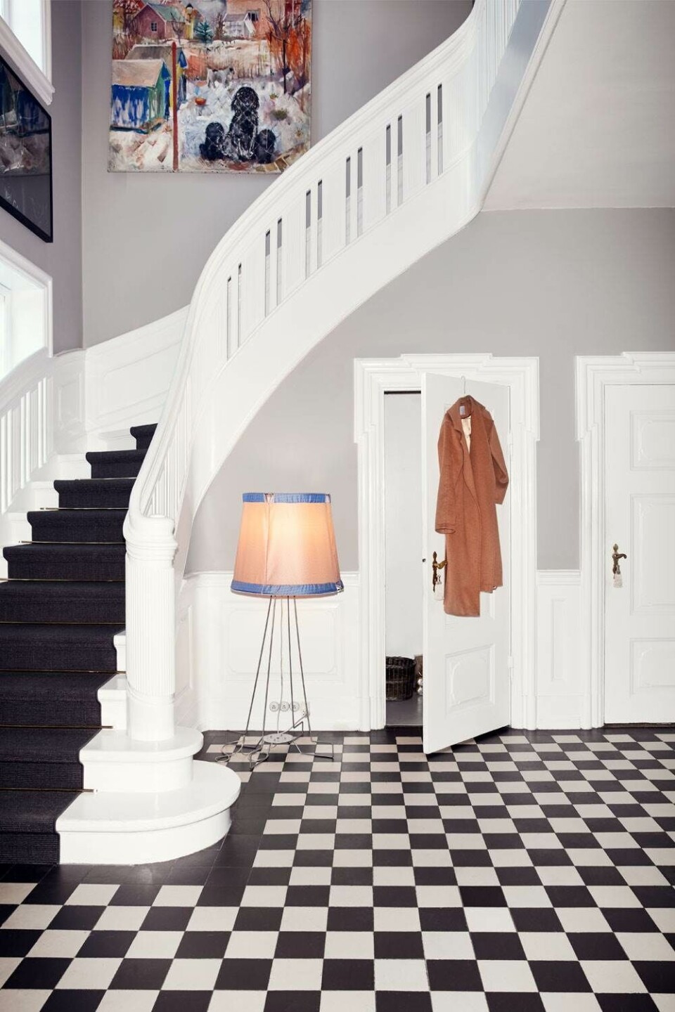 Majestætisk entré. Lampe fra Piet Hein Eek og klassisk kameluldsfrakke fra Max Mara. Værket på endevæggen er af Marie Wandel.