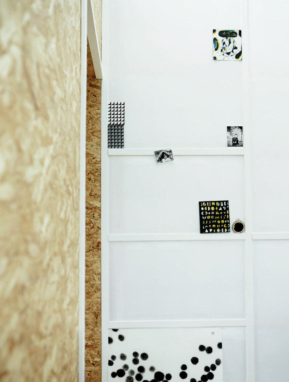 Skillevæggen mellem soveværelset og det centrale rum består af hvidmalede lister betrukket med genbrugsstof.