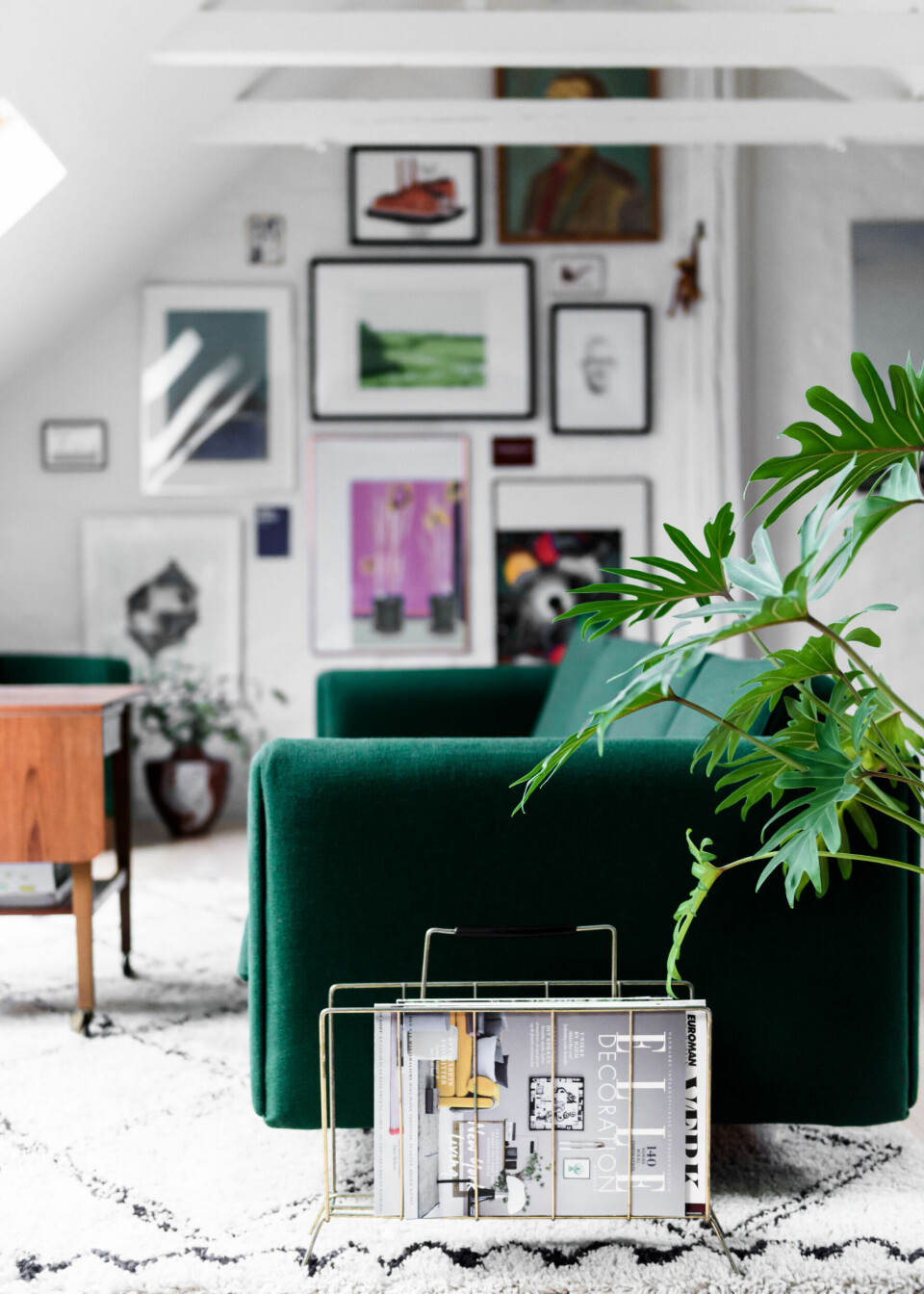 Vægge og bjælker er holdt i hvidt, da der er knald på farverne i både kunst og møbler. Den grønne Wegner sofa er opholdsstuens centrum og placeringen midt i rummet i stedet for op ad en væg skaber en luftig indretning.