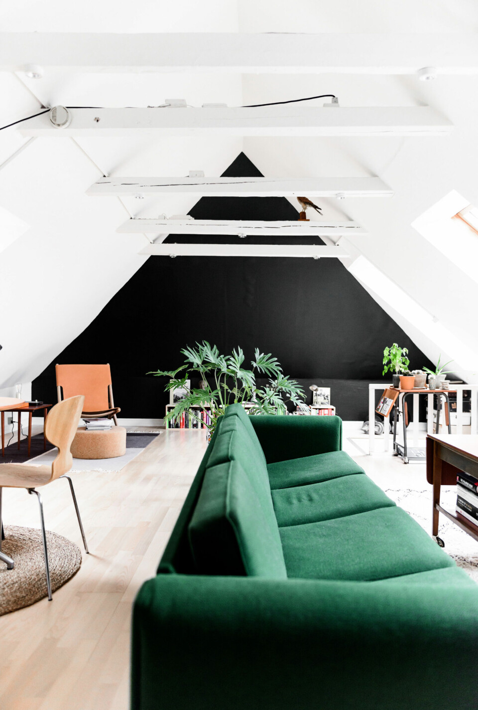 På førstesalen markerer den mørke endevæg de skrå vægge, der giver stuen en hyggelig stemning, samtidig med at farven spiller op til den markante grønne sofa.