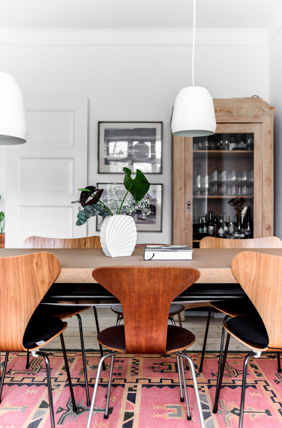 Sarah og Mads elsker at kombinere møbler fra forskellige tidsaldre. I spisestuen står et nyere Ikeaord i kork og rundt om gamle stole i teak og valnød designet af Arne Jacobsen. De to hvide pendler er designet af Cecilie Manz.