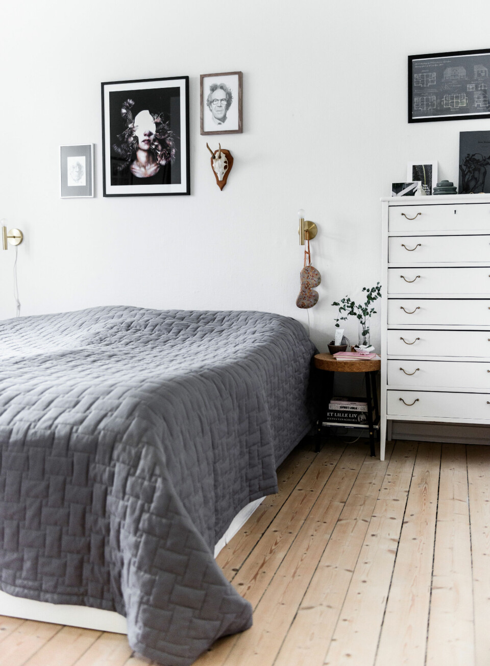 Soveværelset er holdt i lyse og afdæmpede nuancer. Billedvæggen er et miks af Mads’ blyantsstreger, kunsttryk og et gammelt gevir. Den lille korkskammel er fra Ikea, sengetæppet er fra Magasin og den store hvide kommode er fra Sarahs barndomshjem.