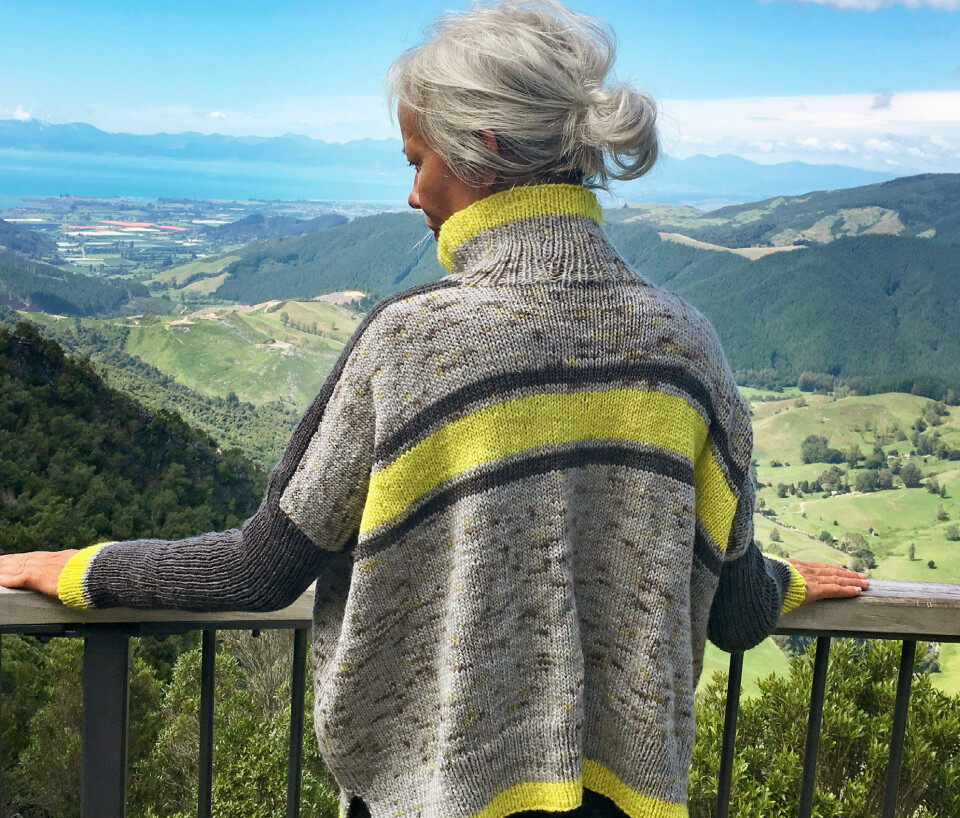 Trine nyder udsigten på Takaka Hill. Hun er iført sin Geraldinesweater, der er strikket i Maniototo wool, som findes i standardfarver, men også i den skønne neongule, der giver trøjen spræl.