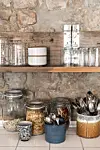 Gamle træpaller og drivtømmer er en gennemgående del af indretningen. Her i form af en hylde i køkkenet til kopper, kander og glas.