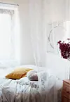 I det superfeminine soveværelse er pladsen udnyttet optimalt. Sengen står langs vinduet, og Charlotte har lavet en moderne alkove ved at hænge et gardin op foran sengen.