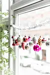 Nanna har en så stor samling af gamle julekugler, at der ikke er plads til dem alle på træet. Derfor er de sat på snore og pynter nu også på rad og række i flere vinduer.
