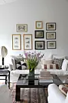 Fin stue med billeder og blomster på bordet.