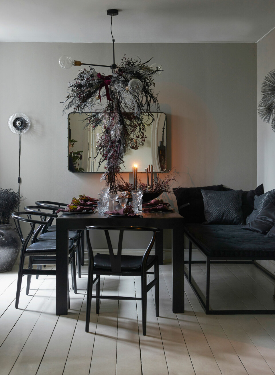 Spisestuen er både dramatisk, mørk og mættet i sit udtryk, og når Rikke har pyntet julebordet, bliver stemningen helt filmisk i spisestuen, hvor en af hendes blomsterskyer hænger over spisebordet, der er kinesisk og vintage. Spisebordsstolene er fra Wegner, og daybedden er speciallavet med en madras fra Rabens Saloner. Den store krukke med sortfarvede, tørrede blomster er fra Rabens Saloner.