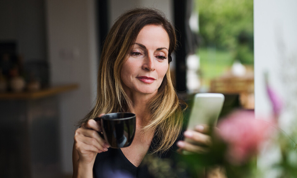 Kvinde kigger op sin telefon