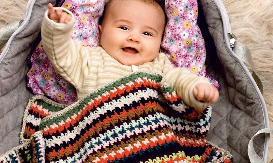 Baby med hæklet barnevognstæppe