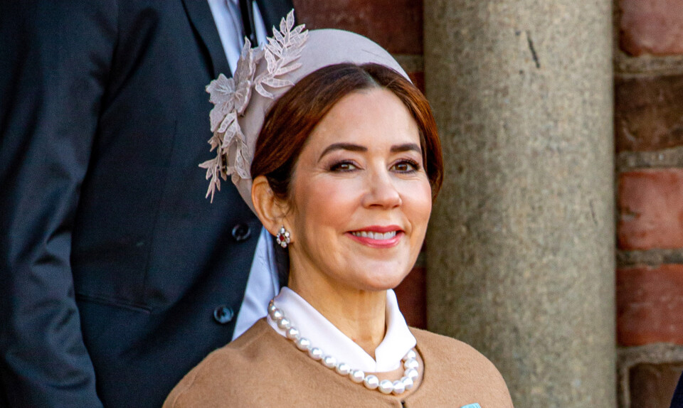 Dronning Mary smiler med rosa hat og perlekæde