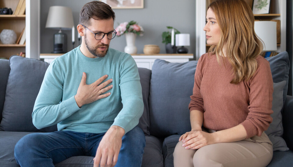 Et par sidder på en sofa og har en samtale i gang.