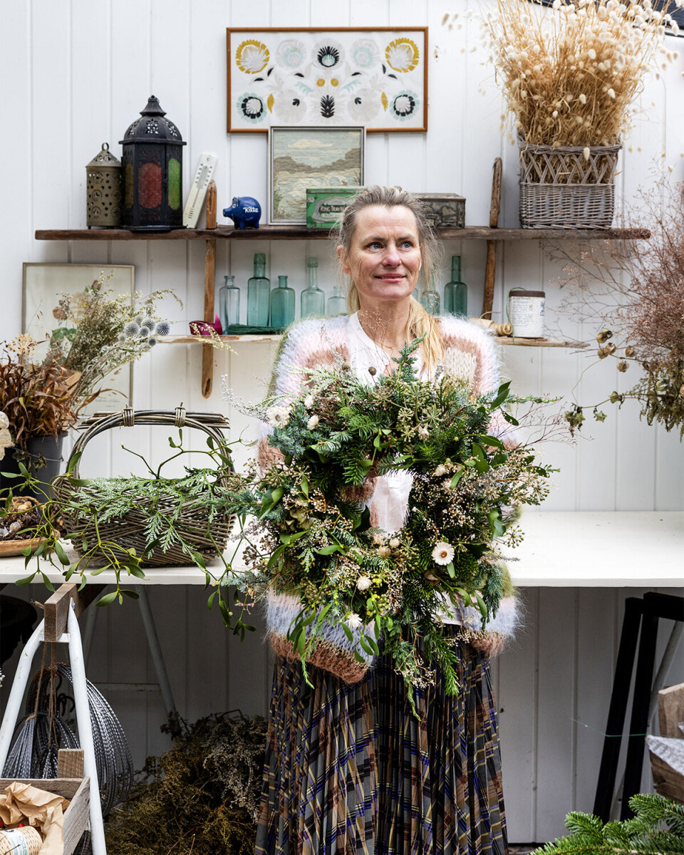 Rikke Lentz’ krans er bundet løst af efeu med bær på, flere typer gran, enebær, tuja, kantbæger, tørret brudeslør, imonium, sølvbynke, mistelten, høstanmone og hvid helichrysum. Alle planterne i Rikkes krans er fra egen have, og kransen er bundet med løs hånd og
med masser af grene og grønt.