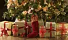 Et juletræ med lys på, og pakker, som ligger under træet.