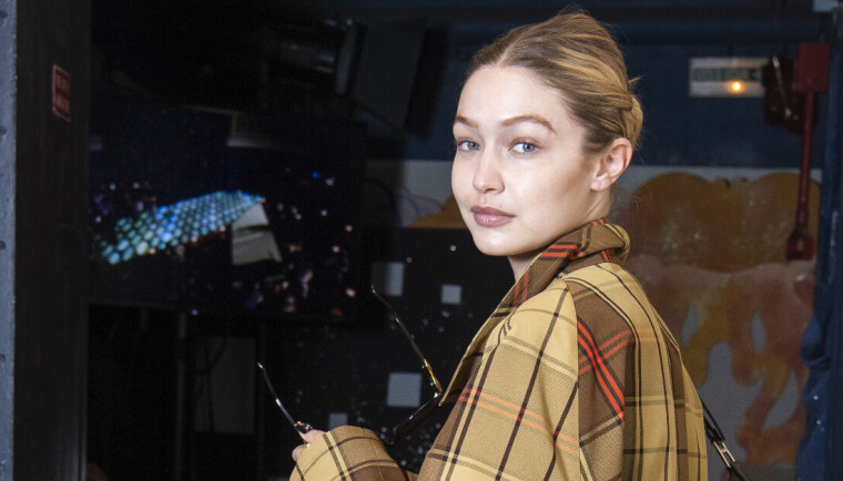 Gigi Hadid står med en ternet vinterjakke på og smiler til kameraet