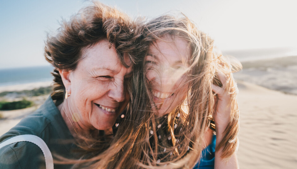 To kvinder griner og krammer på stranden