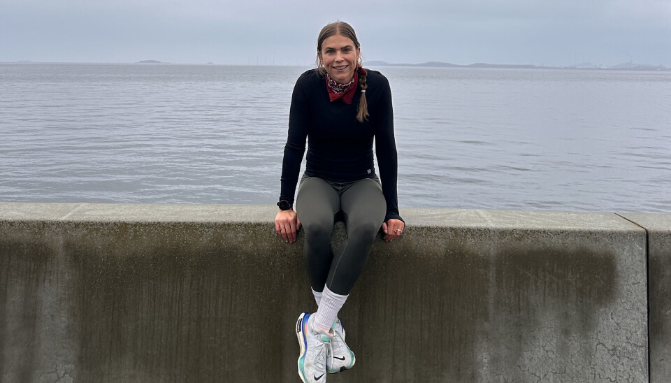 Marie Louise Cramer. Hun sidder på en beton kant, med havet i baggrunden. Hun er i ført løbetøj og løbesko.