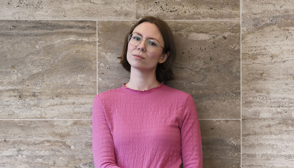 Portræt af Emma Libner. Hun har en lyserød trøje på, mørkt hår, som går til skuldrene og briller på.