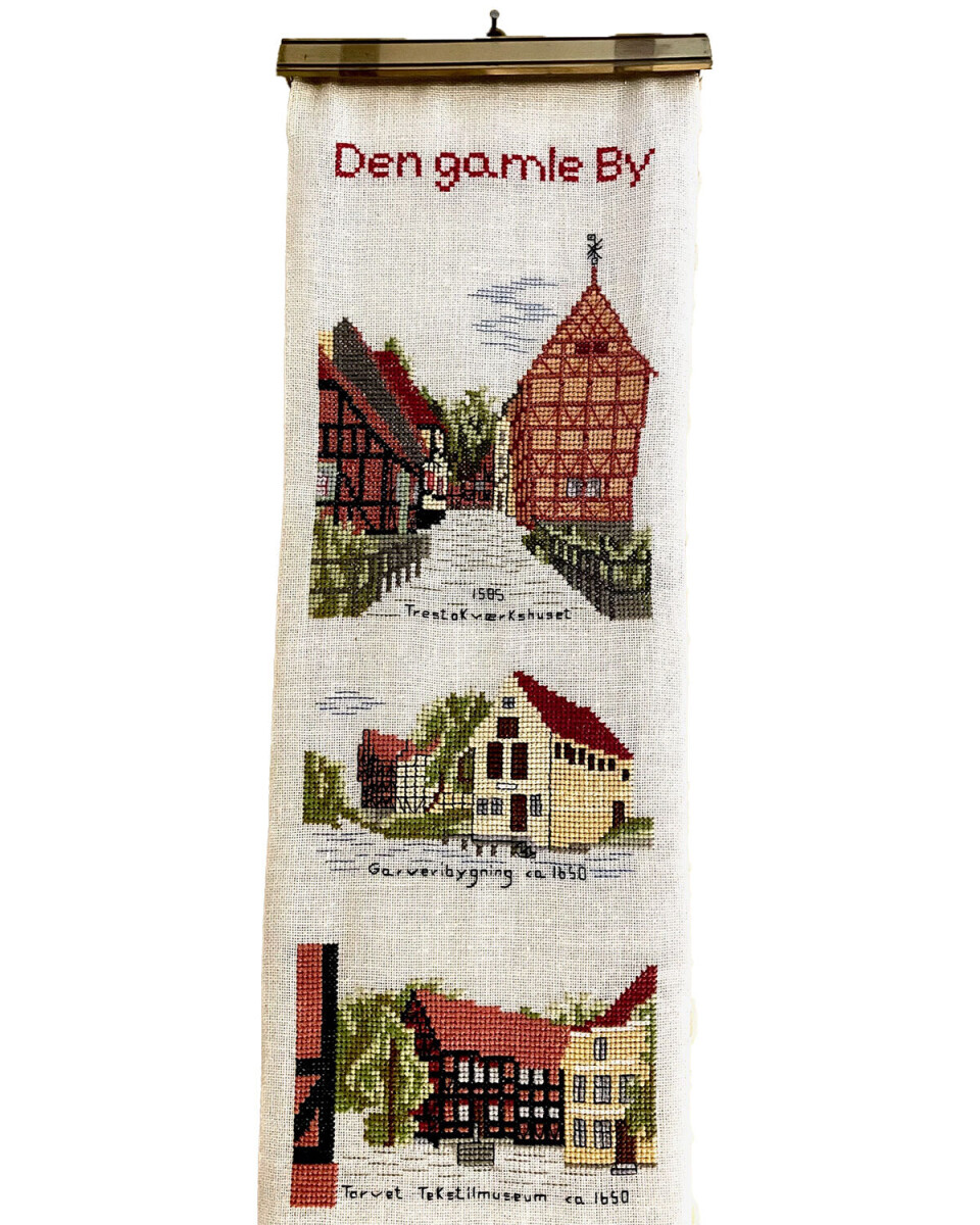 Klokkestrengen er en klassiker inden for broderi. Her er det en klokkestreng med motiver fra Den Gamle By i Aarhus, som hænger i en lejlighed i Den Gamle By, som er indrettet med effekter fra 1950’erne.