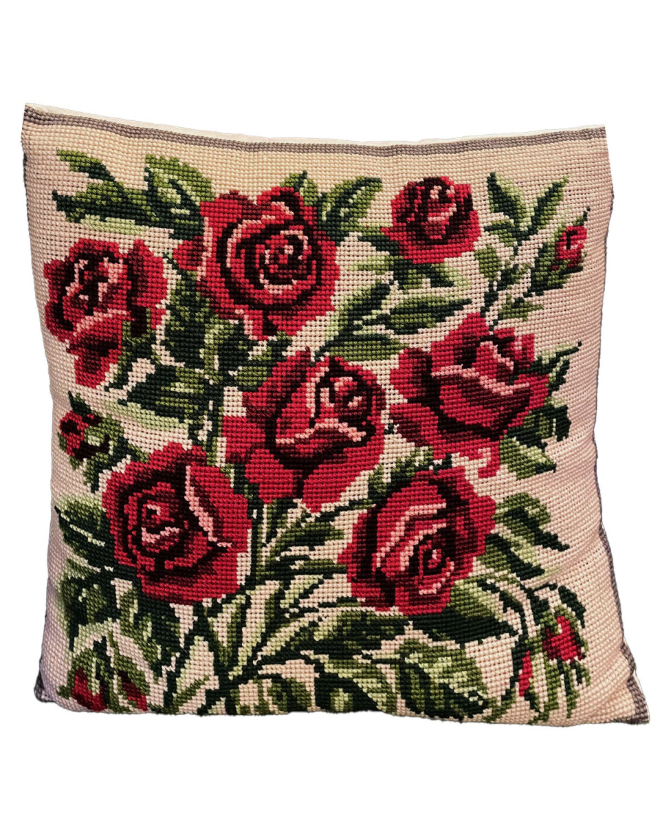 Dekorativt i et hjem fra 1950’erne med en broderet pyntepude med røde roser og grønne blade, som symboliserede elegance og romantik.