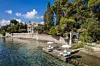 Den smukke Villa Posillipo på Korfu, hvor serien 'The Durrells' er optaget. Her ses fire liggestole ned til vandet og villaen i baggrunden.