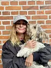 Billede af Camilla Haldrup sammen med sin hund, Bobby. Hun har kasket på og smiler til kameraet.