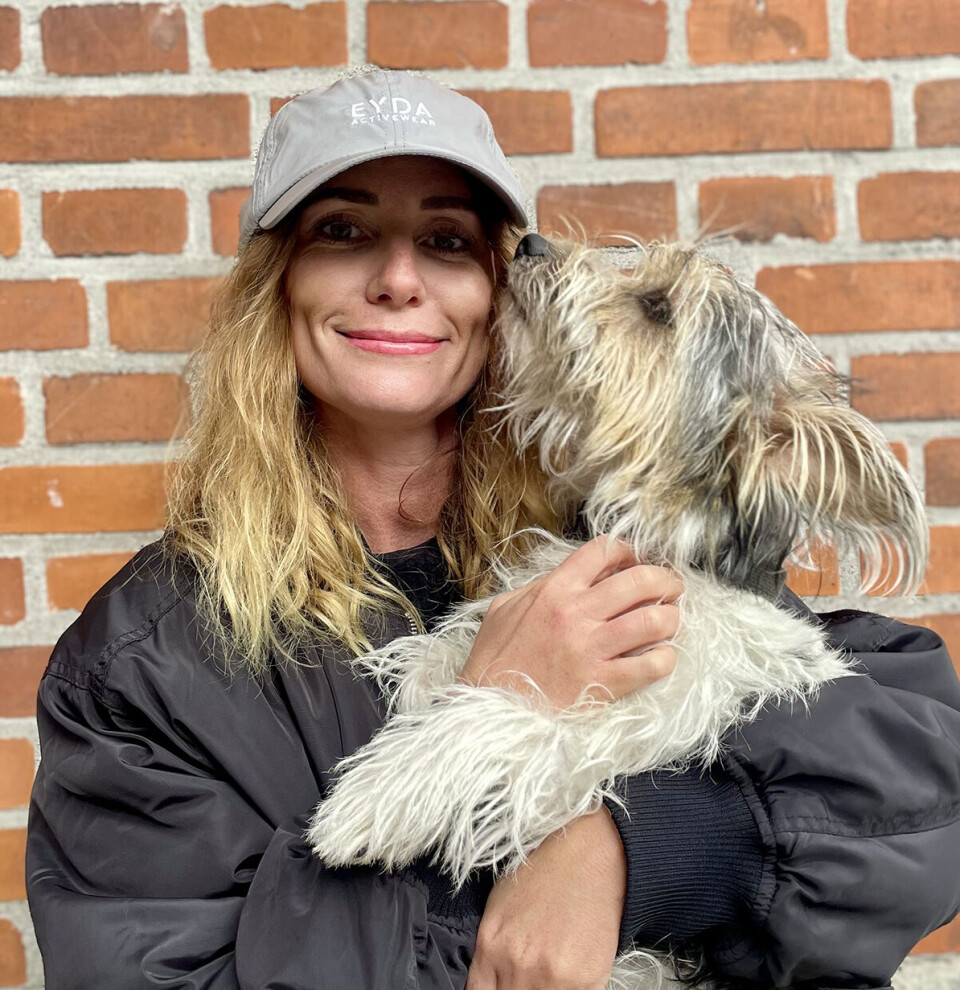 Billede af Camilla Haldrup sammen med sin hund, Bobby. Hun har kasket på og smiler til kameraet.