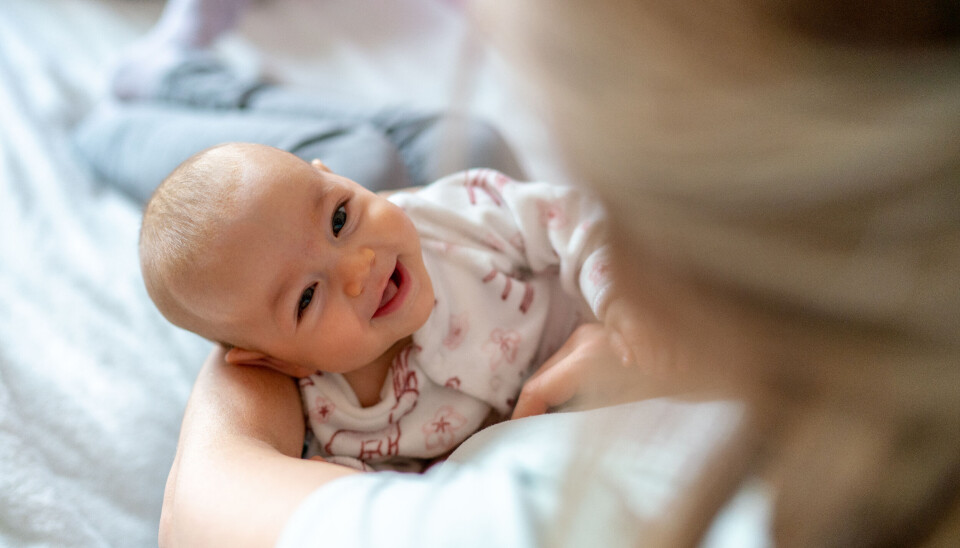 Mother carrying her smiling baby girl at home