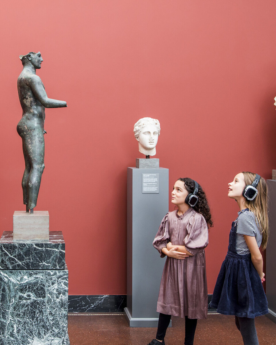 To piger på omkring 8-10 år står og kigger på en skulptur på Glyptoteket.