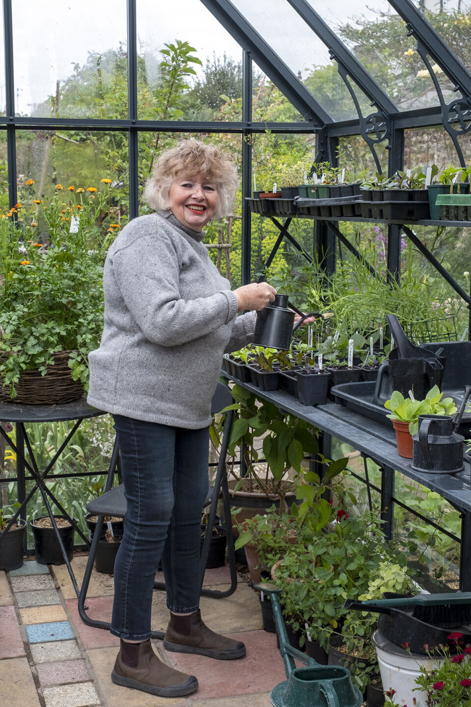 Bridgette i sit drivhus omringet af planter