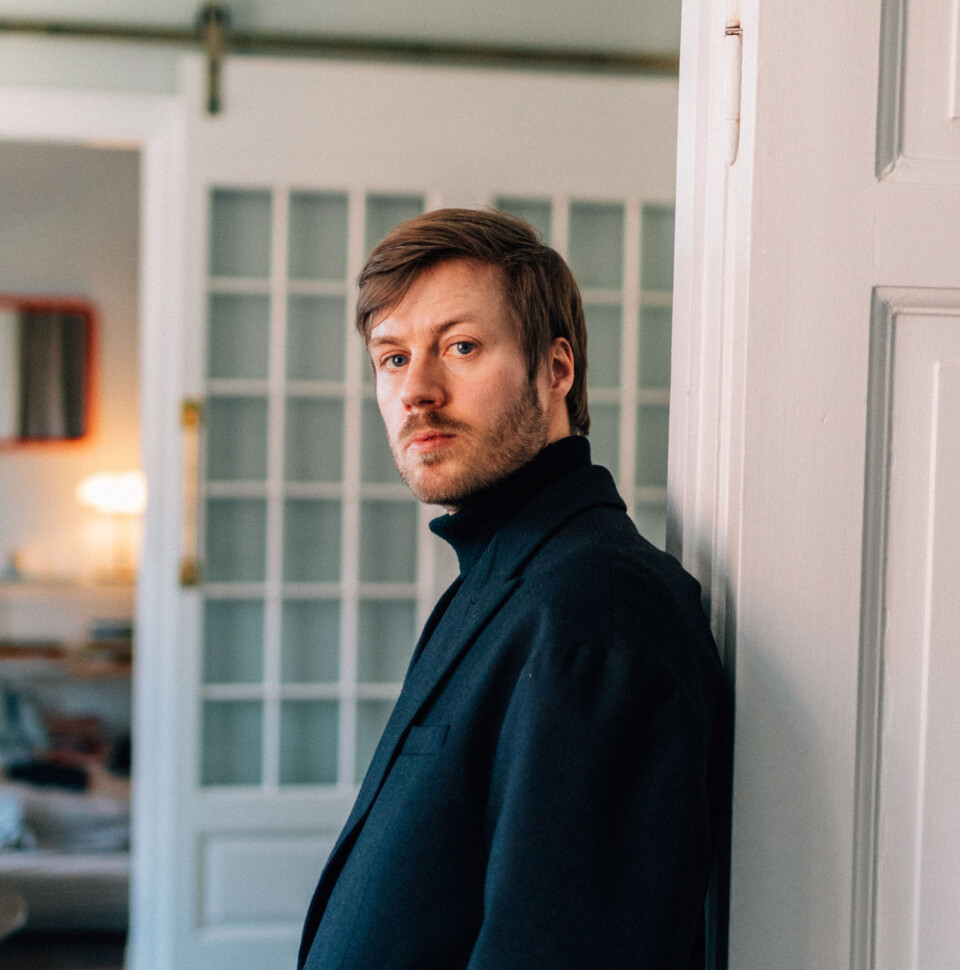 Portrætfoto af Morten Svane, der står lænet op ad en dørkarm i sort blazer og rullekrave.