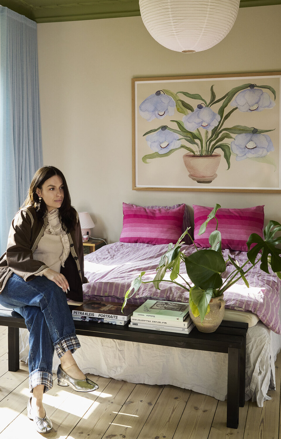Sanja Alexandra i sit soveværelse, hvor hun sidder på en bænk for enden af sengen. Hun kigger til siden.