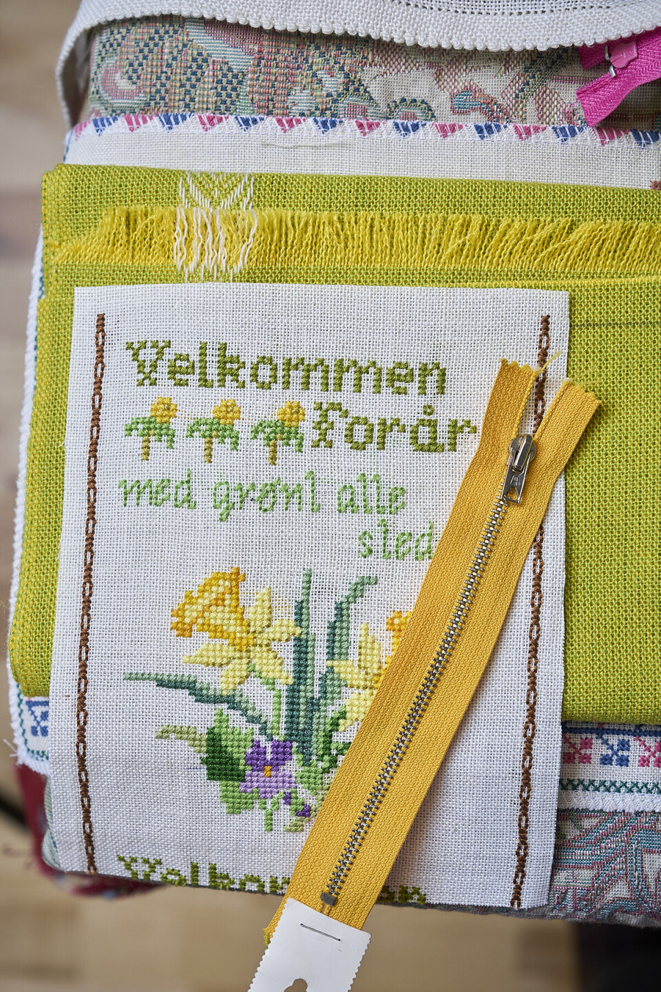 Broderier af Lise Jensen. Ovenpå dem ligger en gul lynlås.