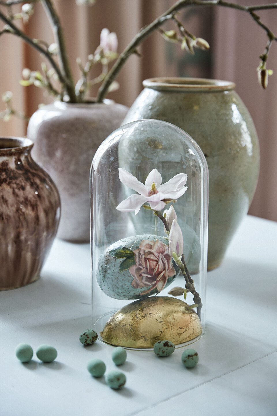 Påskeæg og en blomst under en glasklokke.