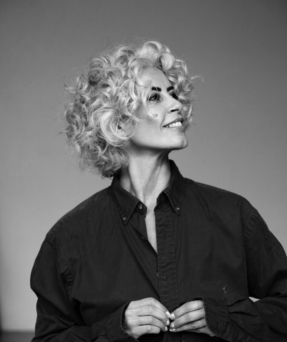 Sort/ hvidt billede af stylist Anja Camilla Alajdi, som i lægger sine krøllede lokker i hænderne på frisør Ofia Seghaou.