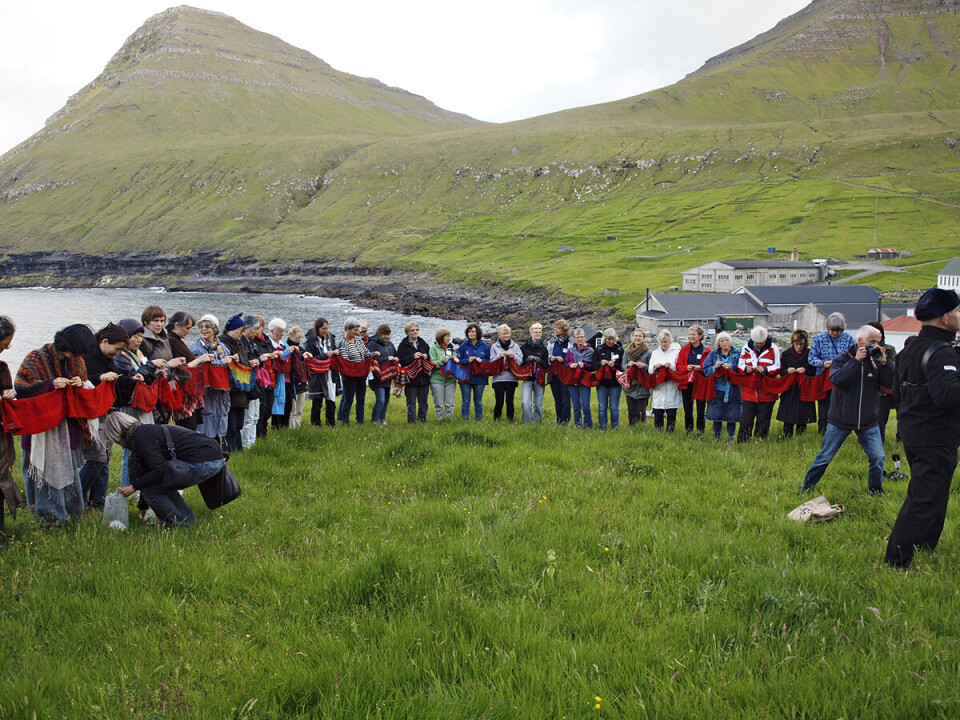 Deltagere ved Nordisk Strikkesymposium i 2011, som blev afholdt på Færøerne. Her ses deltagerne udenfor med grønne bjerge i baggrunden, imens de strikker på den svenske kunstner Kerstin Lindstrøms værk, hvor alle deltagerne medbragte rødt strikketøj og strikkede det sammen.